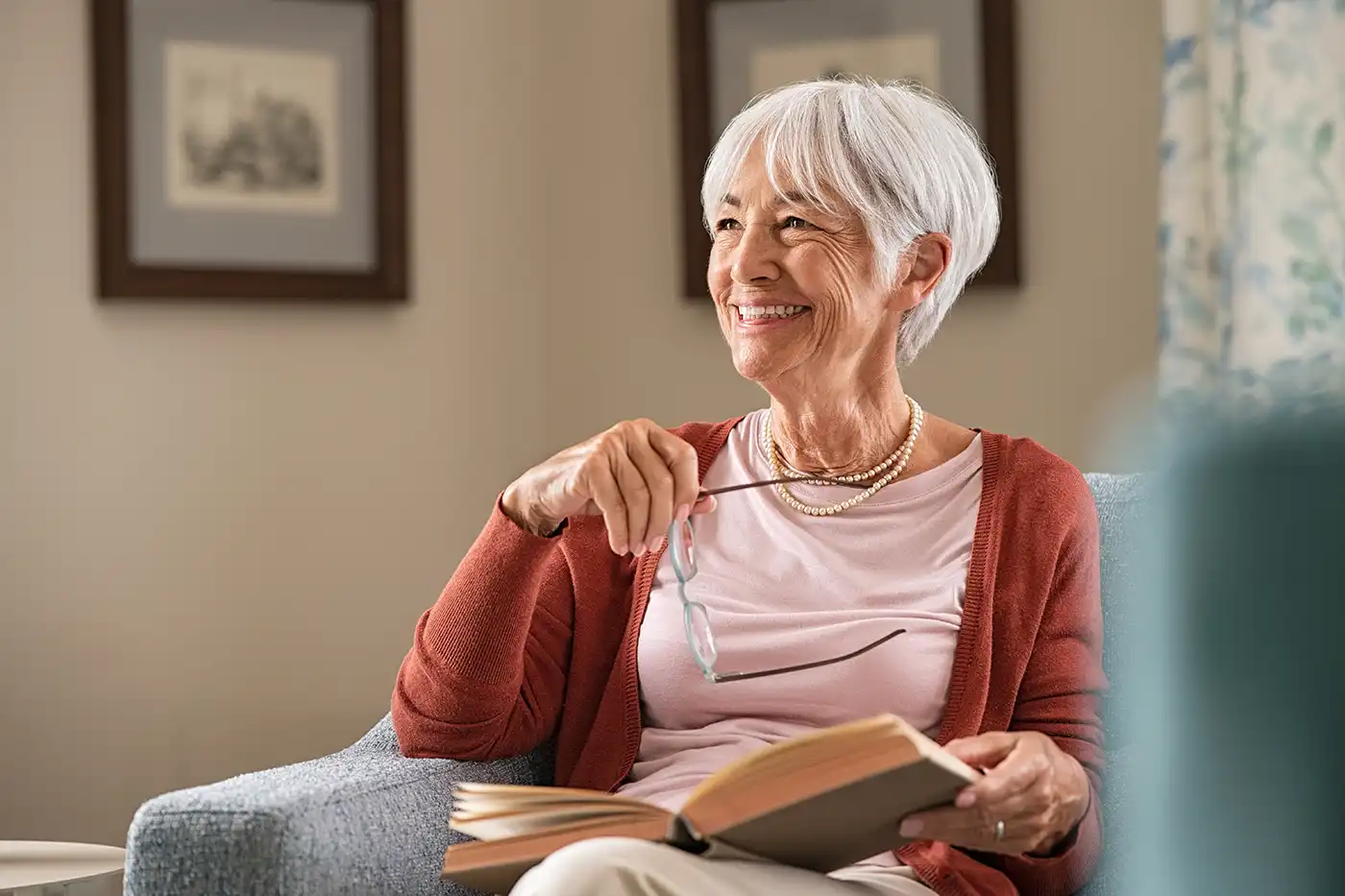 A senior woman taking a break from reading a hardcover book